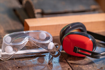 A protective mask and headphones lie on a woodworking machine.