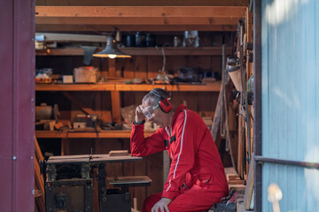 A man is resting in his workshop after work.