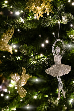 Festive decoration of a ballerina figurine on a Christmas tree with sparkling garland lights, selective focus