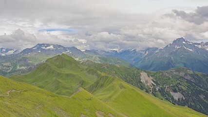 Naklejka premium mountain landscape with green meadow and granite peaks with glaciers under a cloudy sky in La Vanoise nature reserve, Savoie, France 