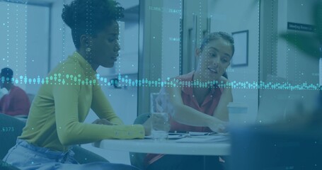 Two office colleagues collaborating on charts in office common area, with digital overlay