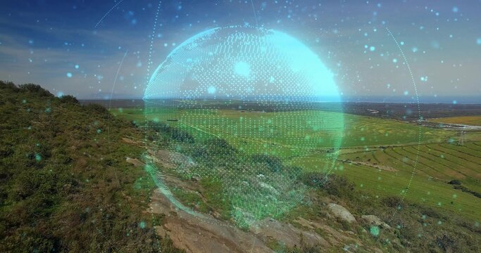 Displaying digital holographic globe floating above hillside, near rocky footpath toward farm plots