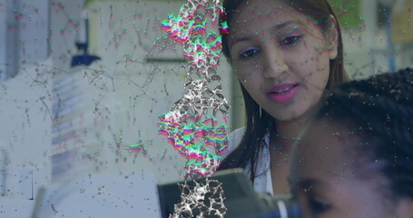 Leaning Indian researcher in lab coat guiding assistant on microscope at bench, copy space