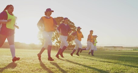 Obraz premium Running seven softball players warming up on softball field in low sun, wearing pinnies and cleats