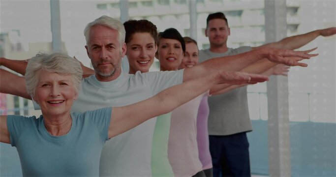 Leading senior woman guiding arm stretching in studio with windows, wearing blue top, copy space