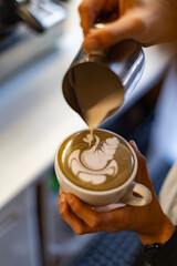 hand holding coffee mug pouring latte art