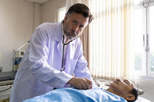 Doctor examining elderly patient in hospital bed