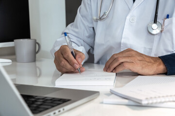 Healthcare professional in lab coat diligently working on a laptop, with stethoscope nearby, representing modern medical practice