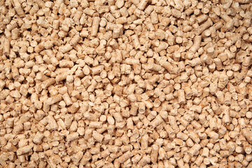 Wood pellets texture. Top view of many pressed pine pellets or softwood granules. Cat litter alternative to clay litter. Used as bio or fuel pellets for heating in stoves or furnaces. Selective focus.