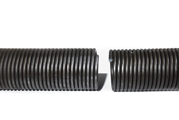 Isolated broken garage door spring or torsion spring from overhead sectional door. Large...