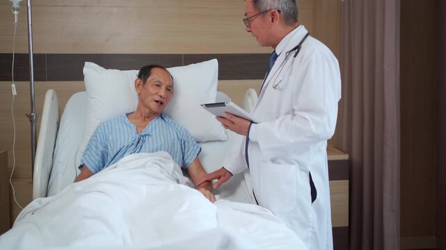 Doctor checking elderly Asian patient and recording notes on tablet.