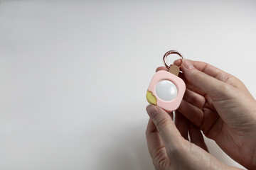 Female hands holding cute GPS tracking keychain shaped like ice cream with copy space
