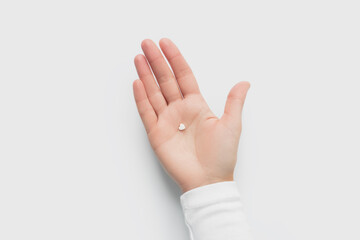 Small White Heart Shaped Pill Held in the Palm of a Hand