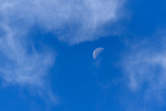 Half Moon in Blue Sky with Wispy Clouds