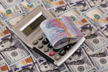 A stack of 10,000 Kazakhstani tenge bills and a calculator for 100 US dollar bills