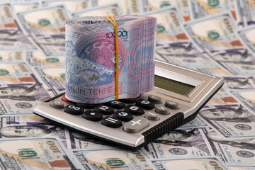 A stack of 10,000 Kazakhstani tenge bills and a calculator for 100 US dollar bills