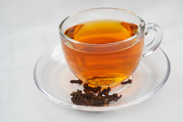 Aromatic hot black tea in a clear glass cup with cloves, a traditional healthy beverage. Enjoy the cozy comfort of spiced red tea or authentic masala chai. Selective focus.