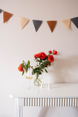 A vase of red roses and an elegant champagne glass on a white table, ideal for any special celebration.
