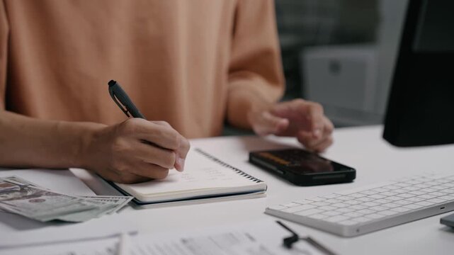 Close up man hand using calculator to calculate home finance and writing note, accounting on table, budget management. Doing finance, budgeting and tax calculation, monthly expenses