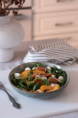 A beautifully vibrant salad composed of fresh peaches, creamy mozzarella, sweet figs, and peppery arugula on white background.