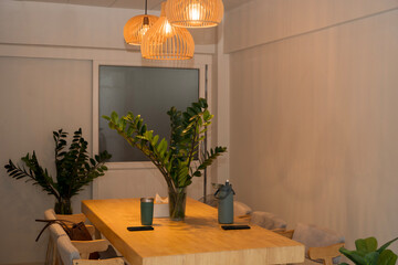 Modern cozy dining room interior with wooden table, green plants, and warm pendant lights at evening