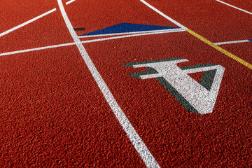 Close up photo of outdoor running track lane white number four, 4, with green shadow, on a new red track with white lane lines.