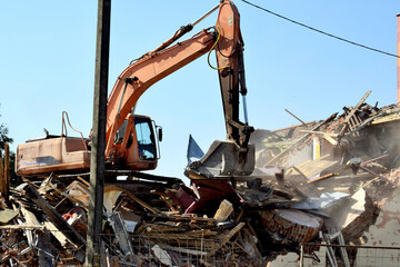 Fototapeta premium A modern excavator clears the rubble of a collapsed building. 
