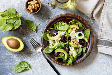Couscous with avocado, beet, fresh spinach and dressing vinaigrette on a grey stone background. Healthy natural plant based vegetarian food, low calories dieting meal.