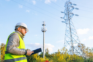 Male engineer maintains a telecommunications tower and power lines. Inspecting 4G and 5G network equipment. Control and maintenance of electrical installations for cellular communications.
