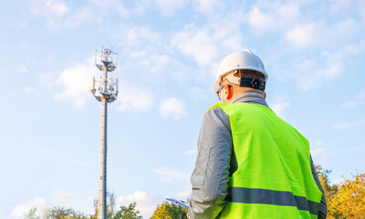 Male engineer maintains a telecommunications tower. Inspecting 4G and 5G network equipment. Inspection and maintenance of cellular communication poles.