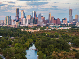 Obraz premium Aerial drone view of the Austin Texas skyline as the full harvest moon is seen rising by the office buildings. Barton Springs swimming pool below