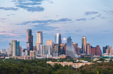 Fototapeta premium Aerial drone view of the Austin Texas skyline as the full harvest moon is seen rising by the office buildings. Zilker Park in the foreground.