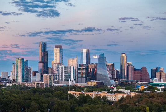 Aerial drone view of the Austin Texas skyline as the full harvest moon is seen rising by the office buildings. Zilker Park in the foreground.