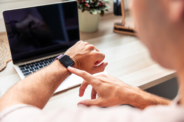 Young man teleworking checking time on smartwatch
