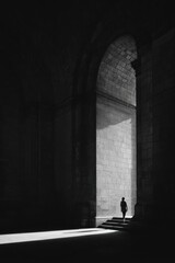 Solitary Figure in Dark Archway with Light Streaming Through Silhouette in Monochrome Setting
