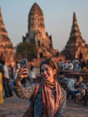 Young Woman Taking Selfie in Historic Temple at Sunset with Tourists in Background
