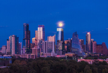 Aerial drone view of the Austin Texas skyline as the full harvest moon is seen rising by the office buildings. Zilker Park in the foreground.