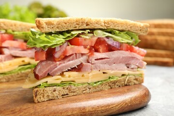 Delicious sandwich with ham, cheese and vegetables on grey table, closeup