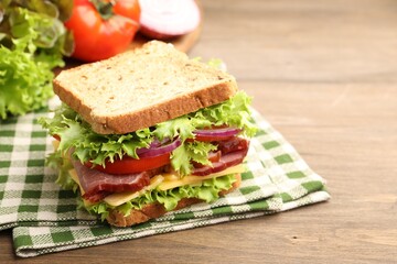 Delicious sandwich with ham, cheese and vegetables on wooden table, closeup. Space for text