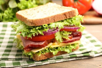 Delicious sandwich with ham, cheese and vegetables on wooden table, closeup