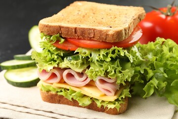 Tasty sandwich with ham, cheese and vegetables on grey table, closeup