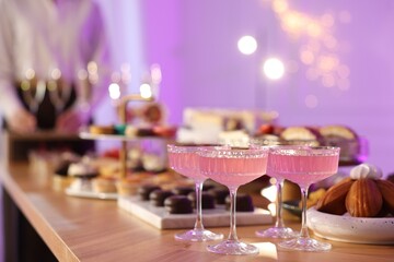 Different delicious desserts, drinks on buffet table and waiter, selective focus