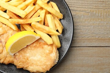 British Traditional Fish and chips served with lemon on wooden table, top view. Space for text
