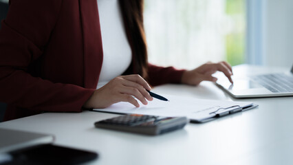 Confident businesswoman sitting at modern office desk reviewing reports and focusing on company tasks