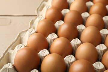 Raw chicken eggs in egg carton on table, closeup