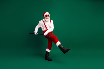 Cheerful santa claus dancing with a cane in red suspenders against a green background bringing festive joy
