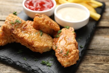 British Traditional Fish and chips with sauces on wooden table, closeup