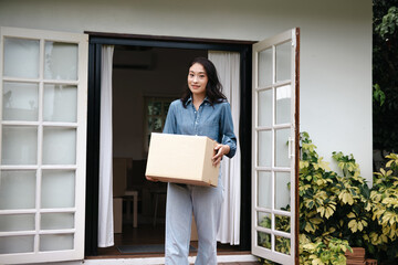 Asian woman moves cardboard boxes to relocate at her new home