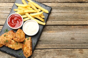 British Traditional Fish and chips with sauces on wooden table, top view. Space for text