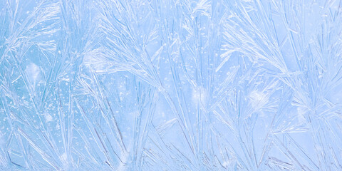 Macro of delicate frost patterns on a blue surface. Thin icy lines form intricate crystal...